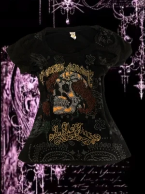 Svart Ed Hardy t-shirt skelett tryck - Cool svart ed Hardy t-shirt från Christian Audigier med Ed Hardy-stil, prydd med diamant detaljerad dödskalletryck och guldfärgade detaljer både fram och bak. T-shirten har korta ärmar, rund halsringning och är tillverkad i mjuk bomull. Perfekt för dig som gillar statement-plagg.