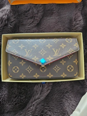 Monogram handväska - Säljer en handväska i brunt med ikoniskt monogrammönster. Helt ny och oanvänd. 