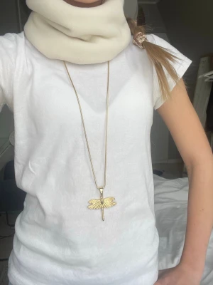 Guldfärgat halsband med trollslända - Guldigt halsband från Ioaku med ett stort hänge i form av en trollslända i. Det finns två stycken kedjor som säljs tillsammans, en lite kortare kedja och en längre beroende på vad man föredrar. Endast lite lite missfärgad längst fram på trollsländan, men absolut ingenting man ser om man inte tittar noga. Annars i väldigt bra. Nypris 500. Skriv för frågor eller fler bilder❤️