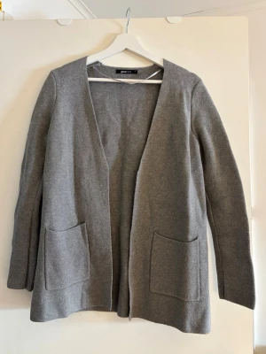 Grå öppen kofta med fickor - Stilren grå kofta från Gina Tricot med öppen front och två stora fickor framtill. Långärmad och i mjukt, stickat material. Säljer då den inte används🩶