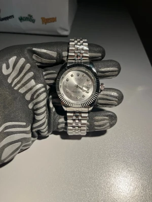 Herrklocka  - 	•	Modell: Datejust 	•	Material: Rostfritt stål 	•	Länk: Jubilee 	•	Bezel: Räfflad 	•	Urtavla: Silver med diamantindex 	•	Glas: Safir 	•	Diameter: ca 36 mm (med box och certifikat 1600kr)