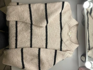Beige stickad randig tröja Gina Tricot - Mysig stickad tröja från Gina Tricot i beige med svarta horisontella ränder. Tröjan har rund hals, ribbade muddar och lång ärm.