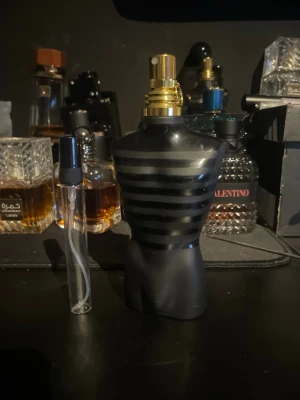 Jean Paul Gaultier Le Male parfym 10 ml sample - Säljer en Jean Paul Gaultier Le Male parfym i den ikoniska svarta flaskan formad som en manlig torso med mattsvarta och blanka ränder samt guldfärgad spraykork. Flaskan är tillverkad i glas och har en unik, stilren design som sticker ut i parfymhyllan. 10 ml bara