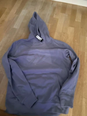 Ljusblå hoodie från lager 157 stl M - Snygg ljuslila hoodie i 100% bomull från lager 157 . Klassisk modell med huva och stor magficka framtill. Perfekt för en avslappnad och trendig stil. Ribbade muddar vid ärmslut och nederkant.