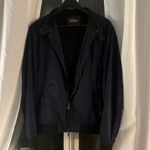 Mörkblå jacka från Oscar Jacobson - Snygg mörkblå jacka från Oscar Jacobson med dragkedja och ribbade detaljer. Perfekt för en stilren look. Jackan har en klassisk krage och är långärmad. 