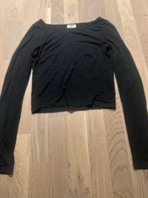 Svart långärmad topp från Kappahl - En enkel och stilren svart långärmad topp från Kappahl. Modellen är croppad med rund halsringning och har en tight passform. Perfekt att matcha med jeans eller kjol för en clean look.