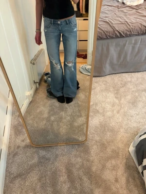Blå  bootcut jeans - Säljer ett par ljusblå bootcut jeans med slitningar och hål på båda knäna. Sitter supersnyggt, pris kan diskuteras och skriv vid fler frågor❤️