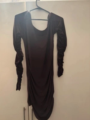 Svart långärmad klänning med rynk, och öppet rygg - Snygg svart långärmad klänning med rynkade ärmar och draperad effekt längs sidorna. Klänningen har en rund halsringning och är figurnära i modellen. Perfekt för dig som gillar en stilren och trendig look. För mer bilder/justering av pris skriv gärna❤️🤗