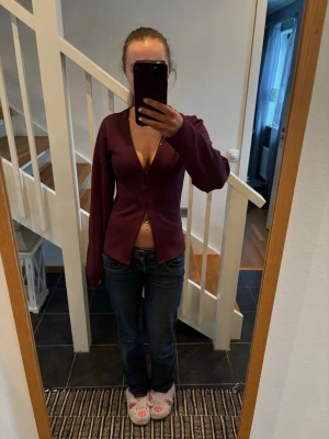 Vinröd kofta ifrån Nelly - Vinröd kofta med djup V-ringning ifrån Nelly. Långa ärmar och figurnära passform. Perfekt att slänga över en topp eller bära som den är. Materialet är mjukt och stretchigt.