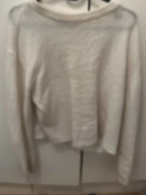 Vit stickad tröja i mjukt material - Klassisk vit stickad tröja med rund hals och långa ärmar. Tröjan är gjord i ett mjukt, mysigt material och har en enkel, avslappnad passform som passar perfekt till jeans eller kjol.