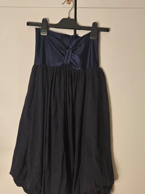 Mörkblå bandeauklänning - Unik mörkblå kortklänning med ballongformad kjol och slät överdel. Den har en bandeau överdel. Den är marineblå och övre delen är väldigt förlåtande mot svett fläckar. Så den är perfekt för sommarn.