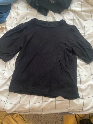 Svart topp med halvlånga ärmar - En enkel svart topp med halvlånga ärmar och rund halsringning. Perfekt basplagg som passar till det mesta. Tillverkad i mjukt material för en bekväm känsla.