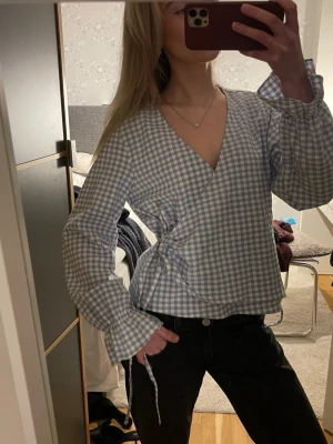 Blårutig omlottblus med knytband zara - Jättefin blus från zara med omlott och knytband i sidan, oanvänd så den är i nyskick!