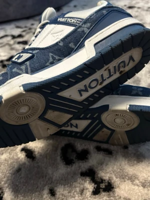 Louis Vuitton blåvita sneakers - Snygga Louis Vuitton sneakers i blått och vitt med klassiskt monogrammönster på textilen. Skorna har vita detaljer, tjock sula och LV-logga på hälen. Perfekta för dig som vill sticka ut med exklusiva och trendiga sneakers.