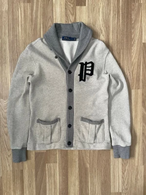 Grå cardigan från Ralph Lauren  - En ljus grå cardigan från polo Ralph Lauren. Tröjan har storleken S och är i mycket fint skick. Skriv vid några funderingar eller behov av fler bilder 😃.