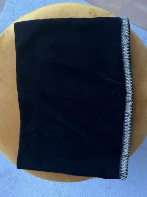 Svart kortkjol med pärlor från Zara - Säljer en svart kortkjol från Zara med en snygg pärldetalj längs nederkanten. Kjolen har en rak passform och är fodrad för extra komfort. Perfekt för dig som vill ha en stilren men ändå glittrig look.