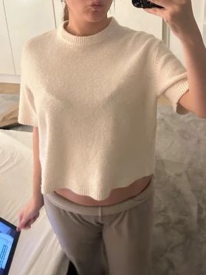 Vit stickad topp - Säljer en krämvit stickad topp med korta ärmar och rund hals. Toppen har en enkel och clean look med ribbade kanter vid hals och ärmslut. Perfekt för dig som gillar en avslappnad men ändå stilren vibe. 💕