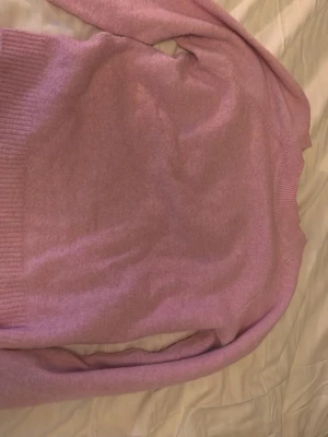 Rosa stickad tröja - Mysig rosa stickad tröja med rund halsringning och ribbade muddar vid ärmslut och nederkant. Tröjan har en enkel och stilren design, perfekt att matcha med jeans eller kjol. Materialet känns mjukt och passar bra för kyligare dagar.