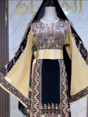 Svart och guld broderad klänning - Palestinsk thobe Unik svart klänning med breda guldiga ärmar och detaljerat broderi i guld och beige. Klänningen har ett brett midjeband, glittriga paljetter och vackra mönster längs kanterna. Perfekt för dig som vill sticka ut med elegans och traditionell touch.
