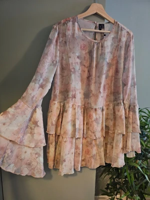 Miniklänning - Vero Moda - Jättefin klänning med volangdetaljer nedtill och vid ärmslut. Breda & långa ärmar. Fastsydd underklänning. Kort modell. Ny med lapp.