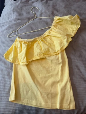 Gul offshoulder topp från Kappahl - Söt gul offshoulder topp från Kappahl med volangdetalj. Perfekt för soliga dagar. Toppen har en axelbandslös design och en ljus, fräsch färg som ger sommarkänsla och passar mig som vanligtvis bär S💛💛💛