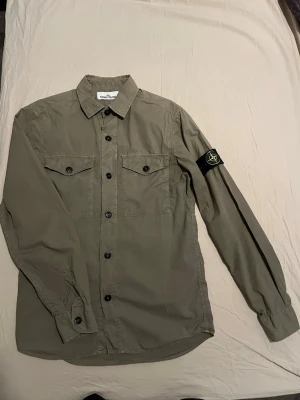 Stone Island Overshirt - Säljer denna riktigt snygga overshirten. Använd någon enstaka gång men skulle själv säga att skicket är 10/10, inga skador eller slitage. Den har 2 fullt fungerande framfickor och badgen är flawless. Nypris 4400kr~. Givetvis är den äkta🙌🙌