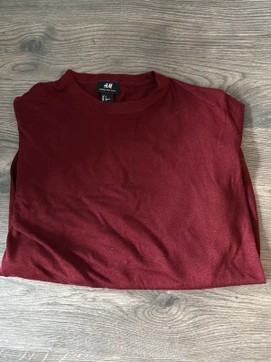 Mörkröd t-shirt från H&M - En enkel och stilren mörkröd t-shirt från H&M. T-shirten har rund halsringning och korta ärmar. Tillverkad i mjuk bomull som känns skön mot huden. Perfekt att matcha med jeans eller shorts för en clean look.