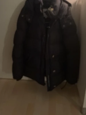 Svart dunjacka med huva - Jätte snygg bomerang jacka. Äkta,nypris 6000. Kedjan går inte hela vägen upp och bör bytas ut där av mitt pris.1500