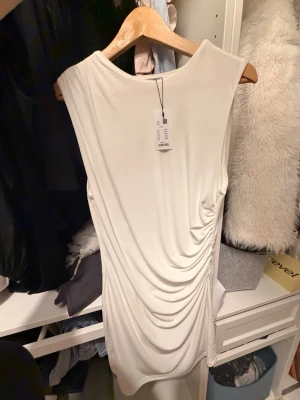 SNYGG VIT KLÄNNING - Snygg draperad klänning från lager!! Säljer samma i svart i profilen, älskar den men passar inte!! Den är oanvänd och borde köpas av nån som den passar 😍😘