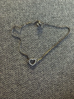 Silverfärgat med hjärtberlock - Ett stilrent silverfärgat armband med en öppen hjärtformad berlock dekorerad med små gnistrande pärlor. Armbandet har en tunn kedja och justerbar låsning med två kulor. Perfekt för dig som gillar diskreta och eleganta smycken. Från ur och penn men vet inte vad det är gjort av men det är silverfärgat. Aldrig använt