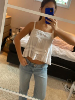 Vit croppad linnetopp med volang - Säljer en vit croppad linnetopp med volangdetaljer och smala axelband. Perfekt för dig som gillar en luftig och lätt stil. Toppen har en avslappnad passform och är riktigt snygg till jeans eller shorts.