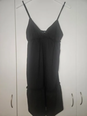 Svart klänning från H&M Divided - Svart klänning från H&M Divided med tunna axelband och v-ringning. Mjukt och lätt material. Enkel och stilren design.