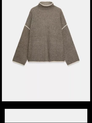 Brun stickad tröja med polokrage - Snygg brun stickad tröja med lös passform och polokrage. Tröjan har vida ärmar och diskreta vita detaljer vid ärmslut och axlar. Perfekt för lager på lager och enkel att styla till olika outfits.