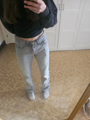 Ljusgrå raka jeans - Säljer ett par ljusgrå jeans med rak passform och klassisk femficksdesign. Jeansen har normal midja och är tillverkade i ett mjukt denimtyg. Perfekta för en avslappnad och trendig look.