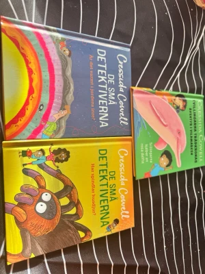 De små detektiverna bokpaket - Säljer ett färgglatt bokpaket med tre böcker ur serien 'De små detektiverna' av Cressida Cowell. Omslagen är i blått, gult och grönt med lekfulla illustrationer av djur och barn. Perfekt för dig som gillar mysterier och äventyr i bokform.