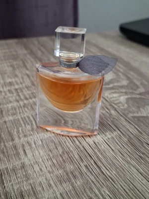 La Vie Est Belle parfym från Lancôme, 4 ml - Säljer en elegant miniatyr parfym från Lancôme, La Vie Est Belle. Flaskan är dekorerad med en liten grå tygrosett vid halsen och ett stilrent, transparent lock i glas. Parfymen beskrivs som , elegant och glädjefull och är en av världens mest sålda parfymer.