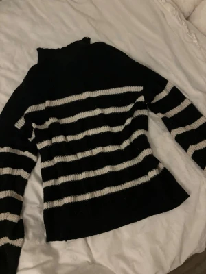 Svartvit randig stickad tröja - Stickad tröja med svarta och vita horisontella ränder. Tröjan har lång ärm och en lite högre hals. Tror det är stl s, den sitter som en s. och vet inte märke, har ingen lapp. Lite nopprig. 