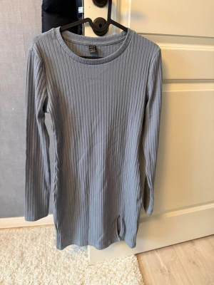 Klänning med liten slits  - Ljusblå ribbad klänning med en liten slots på vänster sida ben. Strl S. 