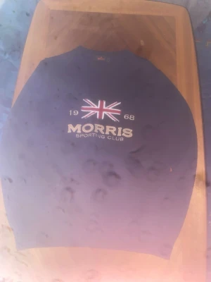 Morris Sporting Club tröja marinblå - Snygg marinblå tröja från Morris Sporting Club med broderad Union Jack-flagga och texten '1968 MORRIS SPORTING CLUB' på bröstet. Tröjan har rund halsringning och ribbade muddar. Perfekt för dig som gillar klassisk och sportig stil.