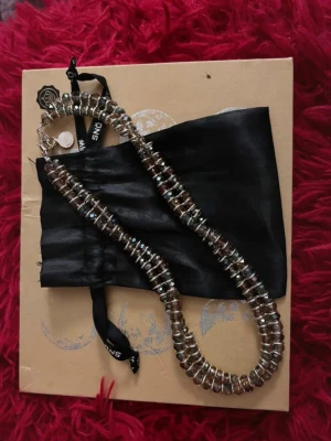 Glittrigt halsband med pärlor - Snyggt halsband från SNÖ of Sweden med glittrande, runda pärlor. Halsbandet har en klassisk form och stängs med ett metallspänne. Perfekt accessoar för att lyfta din outfit. Nypris 700kr