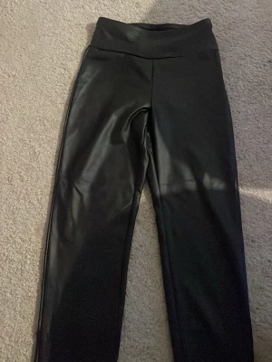 Svarta leggings i fuskskinn - Helt nya Skinnbyxor. Materialet är glansigt och stretchigt för extra komfort.