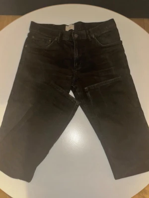 Svarta raka jeans - Säljer ett par svarta jeans med rak passform och klassisk femficksdesign. Jeansen har bälteshällor och knappgylf. Materialet är denim och färgen är djupsvart, vilket gör dem enkla att matcha med olika stilar.