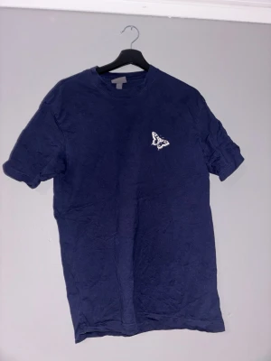 Mörkblå t-shirt med tryck - Mörkblå t-shirt med vit text och fjärilstryck på bröstet och ryggen. Texten på ryggen lyder 'Life Is What You Make It So Make It Well'. Klassisk passform och rund hals. Perfekt för en avslappnad stil.