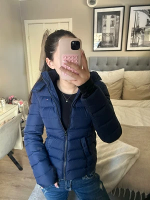 Blå pufferjacka från Tommy Hilfiger - Snygg mörkblå pufferjacka från Tommy Hilfiger med huva och dragkedja framtill. Jackan har två fickor och är i bra skick men kan finnas tecken på användning❤️❤️