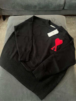  Ami Paris tröja  -  Stickad tröja från Ami Paris med rund hals. Tröjan har breda ribbade muddar vid ärms av originated och nederkant. Perfekt för dig som gillar stilrena plagg. Säljer den då den inte passade