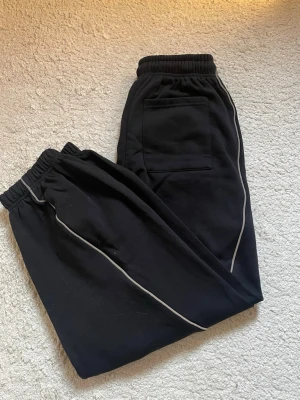 Svarta mjukisbyxor från Björn Borg - Säljer ett par svarta mjukisbyxor från New Yorker med reflex längs benen. Byxorna har resår i midjan och vid bensluten samt en bakficka. Perfekta för chill dagar eller träning. Helt nya, oanvända. Endast testade. Säljs inte längre.