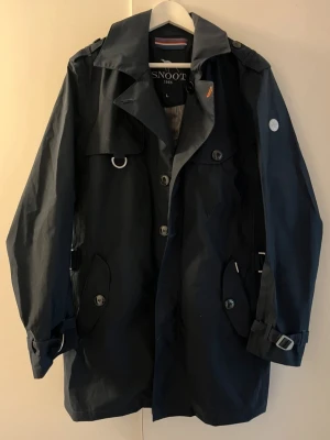 Snoot Jacka  - Snoot Jacka / Trenchcoat i storlek Large. Snygg stilren. I väldigt bra skick. Fina detaljer. Mörkblå i färgen. 