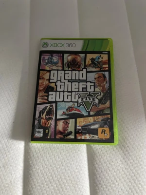 Xbox 360 spel GTA V & FIFA 14 - Säljer två Xbox 360-spel: Grand Theft Auto V från Rockstar Games med ikonisk omslagsdesign och FIFA 14 från EA Sports med fotbollstema. Båda spelen kommer i klassiska gröna plastfodral och är perfekta för gamingkvällar.