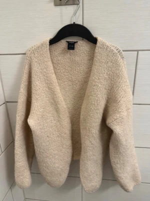 Beige stickad kofta  - Mysig beige stickad kofta från Twilfit med öppen front och avslappnad passform. Koftan har långa ärmar och är tillverkad i ett mjukt, grovstickat material som ger en chill och trendig look.