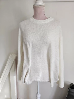 Off white stickad tröja med rund hals - En enkel och stilren vit stickad tröja med rund halsringning och långa ärmar. Tröjan har en avslappnad passform och ribbstickade muddar vid hals, ärmslut och nederkant. Perfekt att matcha med jeans eller kjol för en clean look. Endast testad och tvättad.